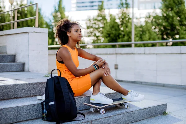 Multiracial Teenage Girl Backpack Skateboard Sitting City Summer Day — Stok fotoğraf