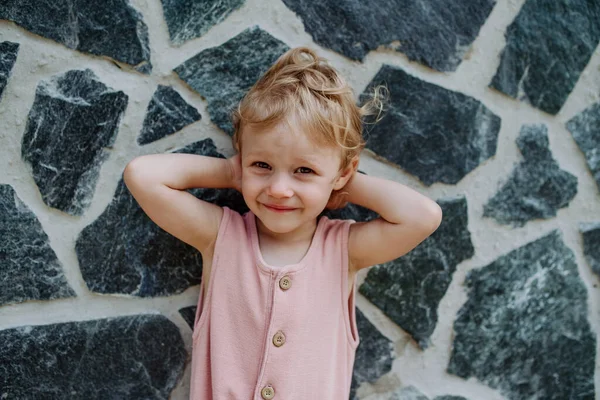 Портрет Маленькой Милой Девочки Позирующей Перед Каменной Стеной Смотрящей Камеру — стоковое фото