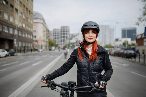 A portrait of businesswoman commuter on the way to work with bike, sustainable lifestyle concept.