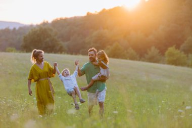 A happy young family spending time together outside in green nature.