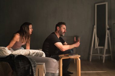 Kıskanç, ihanete uğramış bir kadın kocasını yatakta yastıkla dövüyor. İlişki sorunları kavramı..