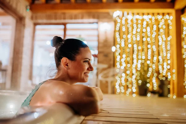 寒い冬の夜にはテラスで露天風呂を楽しむ若い女性 — ストック写真