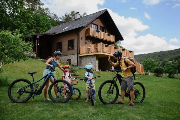 一个年轻的家庭 有小孩 准备骑自行车 在房子前面 — 图库照片