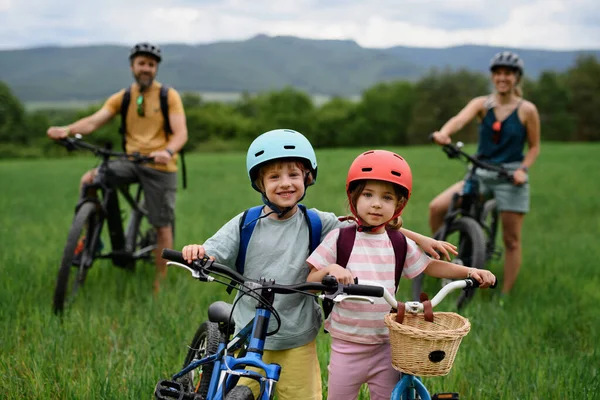 小さな子供が自転車に乗って 自然の中で自転車と一緒に立って休んでいる若い家族の肖像画 — ストック写真