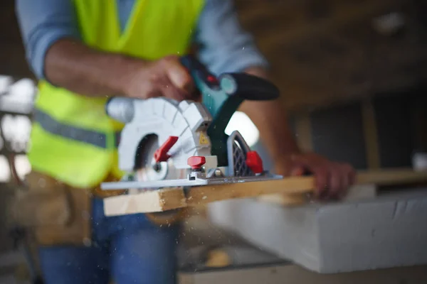 在木制房屋建筑中使用电锯施工的建筑工人的特写 对生态友好型住宅的概念 — 图库照片