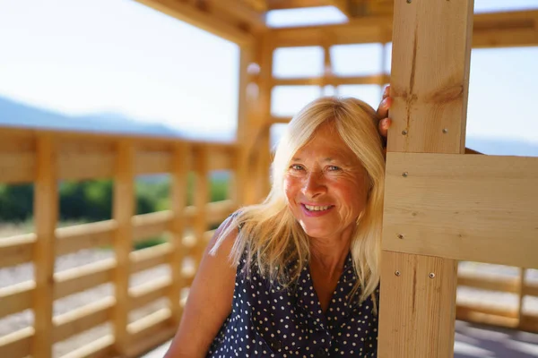彼女の新しい未完成の生態系の木造住宅の中の幸せな先輩女性 — ストック写真