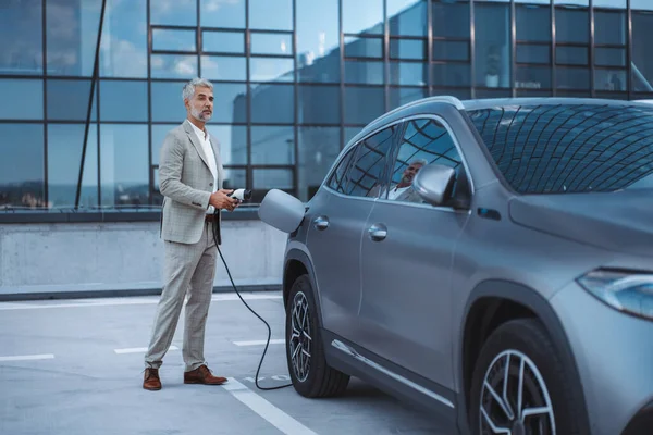 Businessman Holding Power Supply Cable Electric Vehicle Charging Station — Stock fotografie