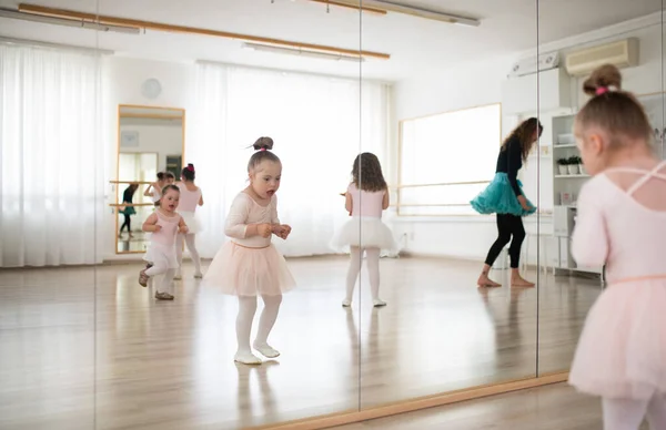 Little girls with down syndrome dancing ballet in a ballet school studio.