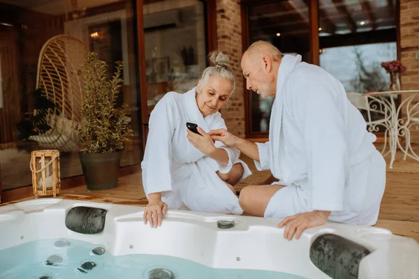 Senior Couple Prepare Outdoor Bath Tub Chcecking Smartphone — Stock Photo, Image