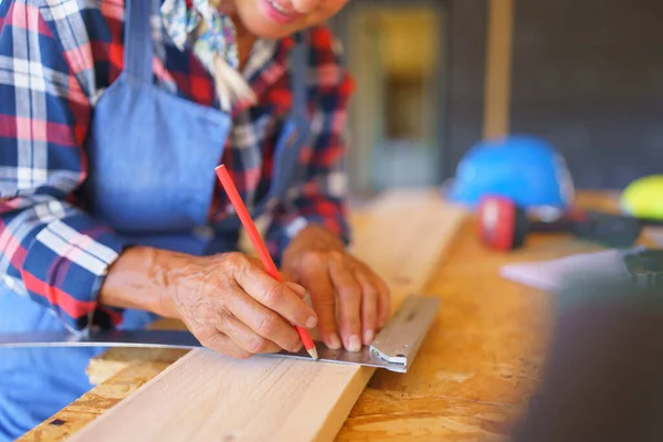 一名高级妇女在其尚未完工的生态木屋内测量木板的特写镜头 — 图库照片