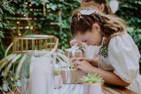 Little girls preparing gift for bride at a wedding garden party.