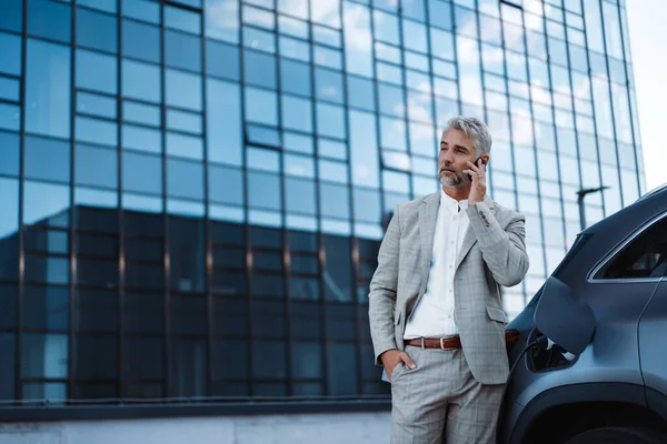 Businessman Holding Smartphone While Charging Car Electric Vehicle Charging Station — Zdjęcie stockowe