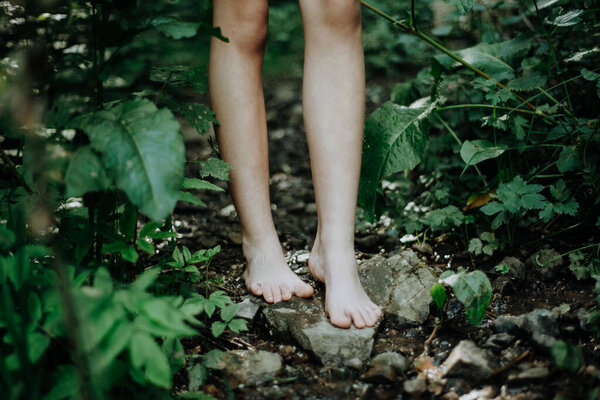 Close-up of barefoot legs walking in the forest. Concept of healthy feet.