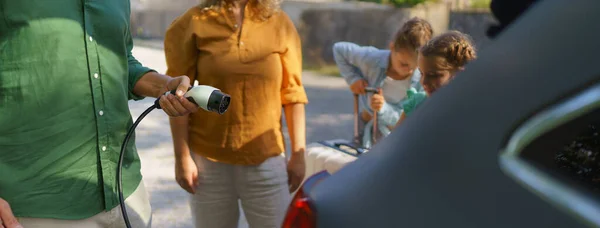 Hombre Sosteniendo Cable Alimentación Mientras Familia Espera Carga Del Coche —  Fotos de Stock