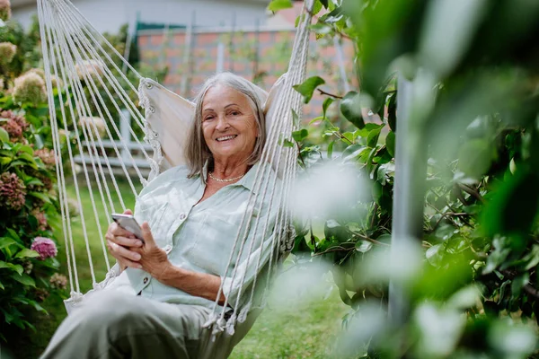 Старша Жінка Розслабляється Садових Гойдалках Смартфоном — стокове фото