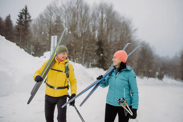 Seniorenpaar Durchquert Winterwald Mit Skiern Auf Schultern — Stockfoto