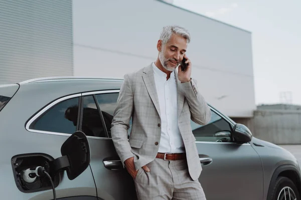 Businessman Holding Smartphone While Charging Car Electric Vehicle Charging Station — ストック写真