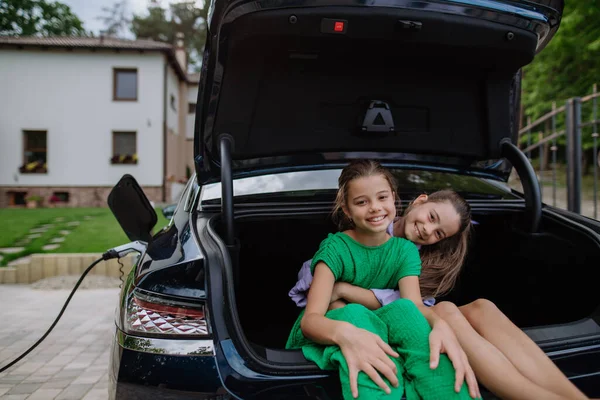 Irmãs Felizes Sentadas Porta Malas Carro Esperando Carregamento Carro Elétrico — Fotografia de Stock