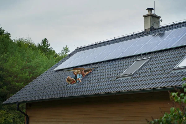 Szczęśliwa Rodzina Wyglądająca Przez Okno Swoim Domu Panelami Słonecznymi Dachu — Zdjęcie stockowe