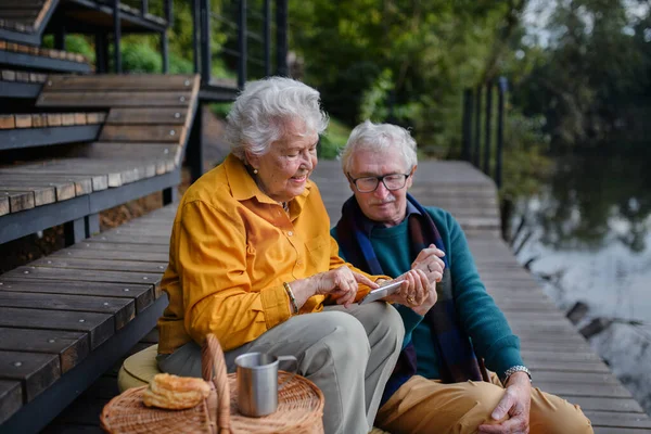 Šťastný Starší Pár Odpočívá Blízkosti Jezera Procházce Při Pohledu Smartphone — Stock fotografie