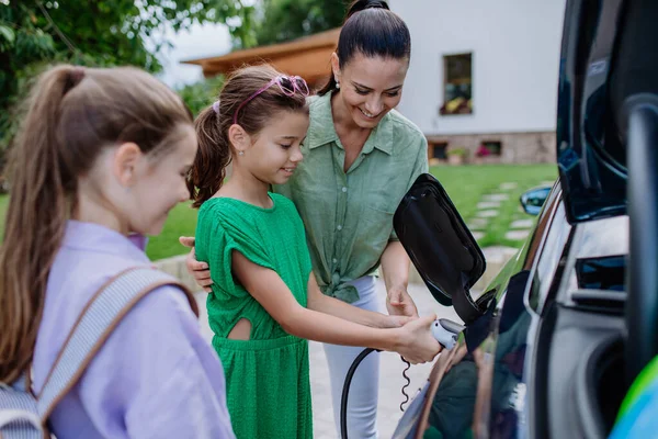 Mère Heureuse Montrant Ses Filles Comment Recharger Leur Voiture Électrique — Photo