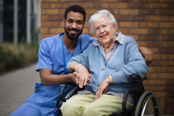一个坐在轮椅上的快乐的老年妇女和她的助手一起在外面度过 — 图库照片