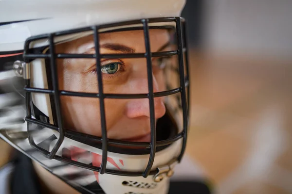 A close-up of woman floorball goalkeeper in helmet concetrating on game in gym.