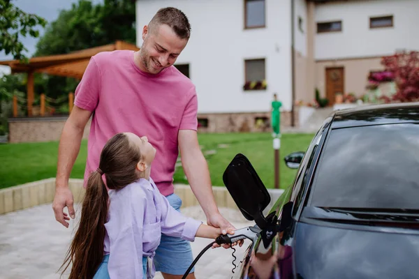 Pai Feliz Mostrando Sua Filha Como Carregar Seu Carro Elétrico — Fotografia de Stock