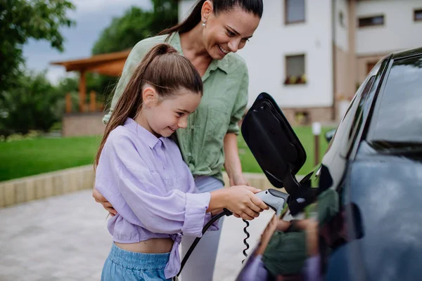 Happy Mother Showing Her Daughter How Charge Electric Car — Stock Photo, Image