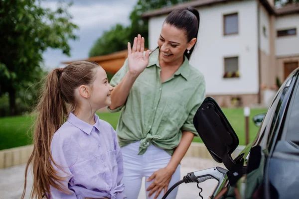 Šťastná Matka Ukazuje Své Dceři Jak Nabíjet Jejich Elektrické Auto — Stock fotografie