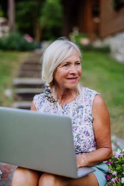 Старшая Женщина Использующая Ноутбук Обрабатывающая Заказы Своих Домашних Органических Цветов — стоковое фото