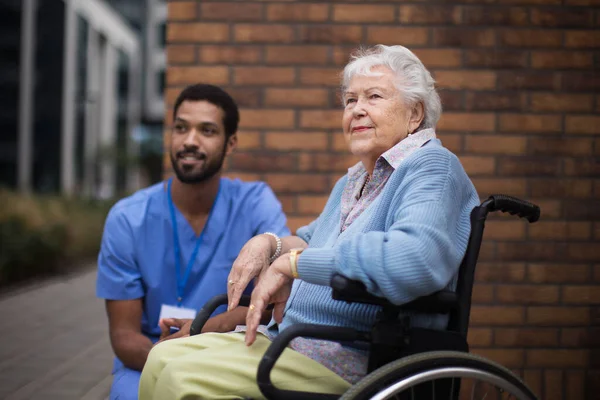 一个坐在轮椅上的快乐的老年妇女和她的助手一起在外面度过 — 图库照片
