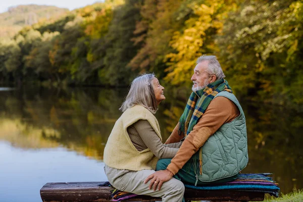 秋天的一天 这对恋爱中的老夫妇一起坐在湖边的长椅上 — 图库照片