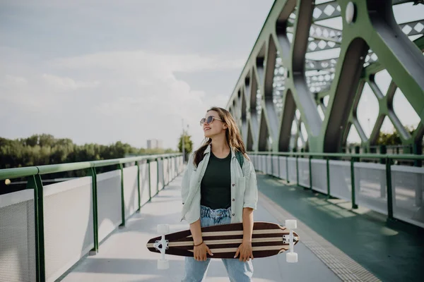 Νεαρή Γυναίκα Που Περπατάει Στη Γέφυρα Της Πόλης Ένα Σκέιτμπορντ — Φωτογραφία Αρχείου