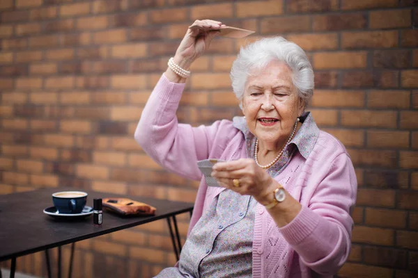 快乐的老年妇女梳理着头发 在城市里喝咖啡 — 图库照片