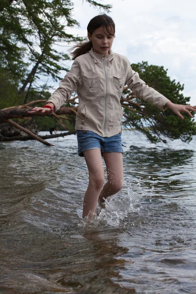 Girl a white jacket walking in the water — Stock Photo, Image