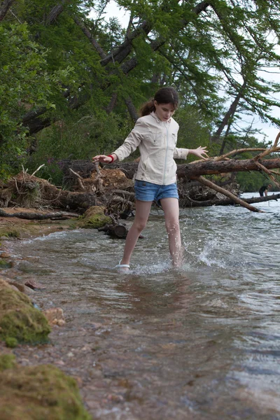 Девушка в белой куртке, идущей по воде — стоковое фото