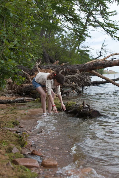 Menina uma jaqueta branca andando na água — Fotografia de Stock