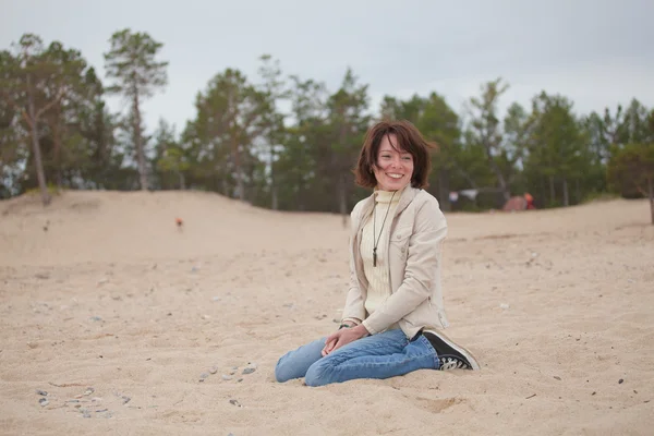 Šťastná žena sedící na písku — Stock fotografie