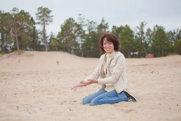 Ευτυχισμένη γυναίκα που κάθεται στην άμμο — Φωτογραφία Αρχείου