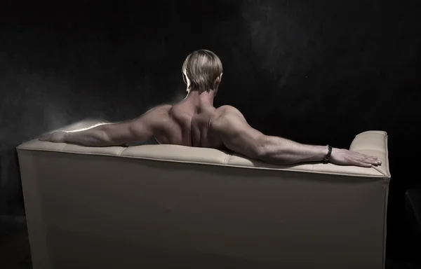 Uomo muscoloso sul divano — Foto Stock