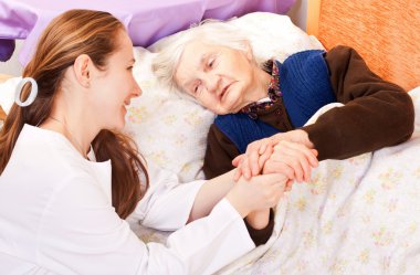 genç doktor, yaşlı kadının ellerini tutar