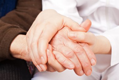 genç doktor, yaşlı kadının ellerini tutar