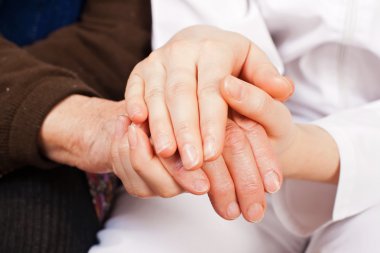 genç doktor, yaşlı kadının ellerini tutar
