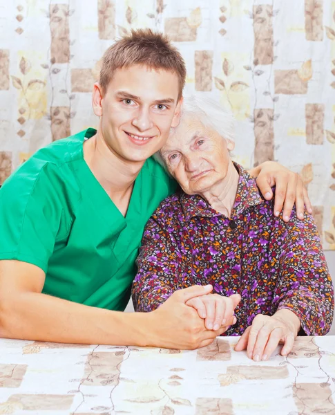 Mujer anciana con el joven médico sonriente — Foto de Stock