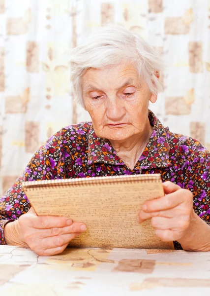 Ältere, glückliche Frau liest etwas aus dem Buch — Stockfoto