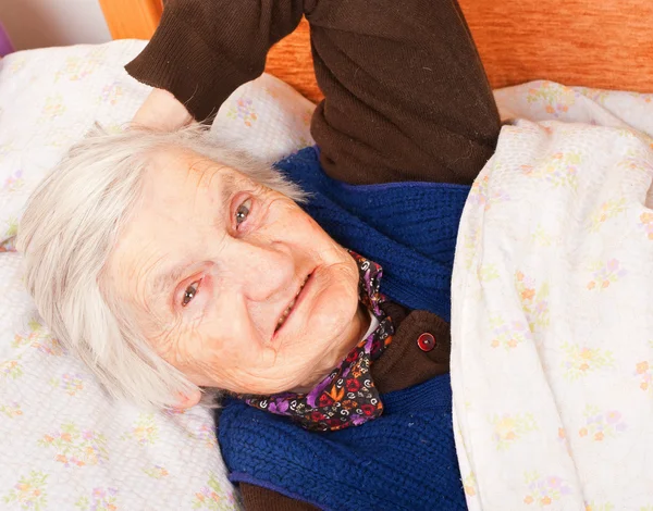 Anciana mujer solitaria descansa en la cama — Foto de Stock