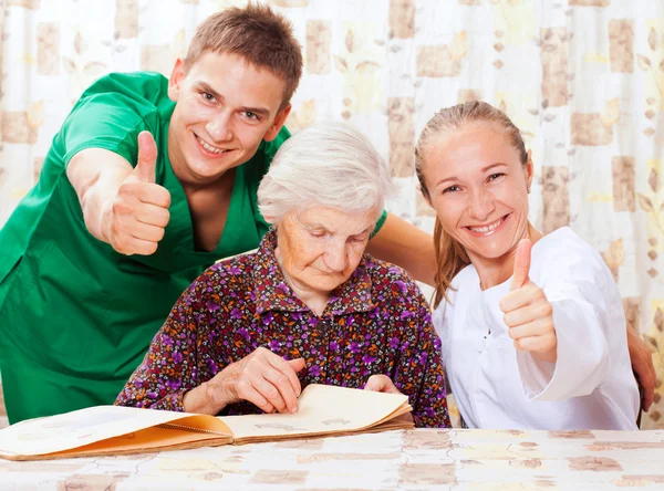 Elderly woman with the young doctors — Stock Photo, Image