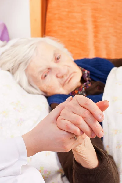 Ηλικιωμένη γυναίκα μοναχικό στηρίζεται στο κρεβάτι — Φωτογραφία Αρχείου