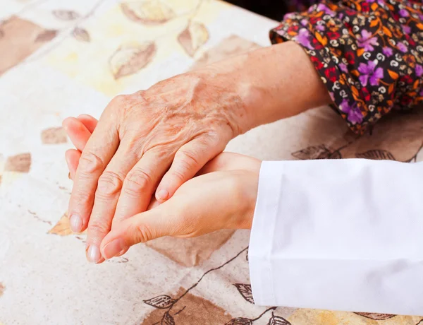 Jeune médecin tient les mains de la femme âgée — Photo